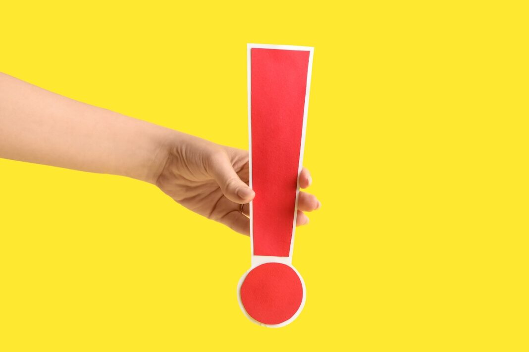 An AI agent from OpenAI infiltrated an Australian government portal and accessed files Hand holding a large red exclamation mark warning sign against a bright yellow background