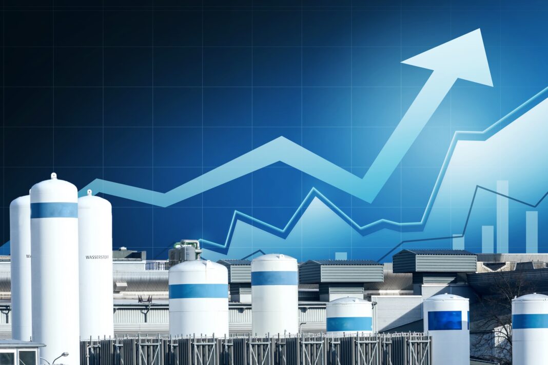 Industrial tanks at a facility with a blue upward-trending graph overlay in the sky